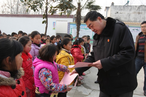 图为2月3日，方城县法院法官张振山在广阳镇后寨小学在为学生们发放寒假安全教育注意事项宣传彩页.JPG